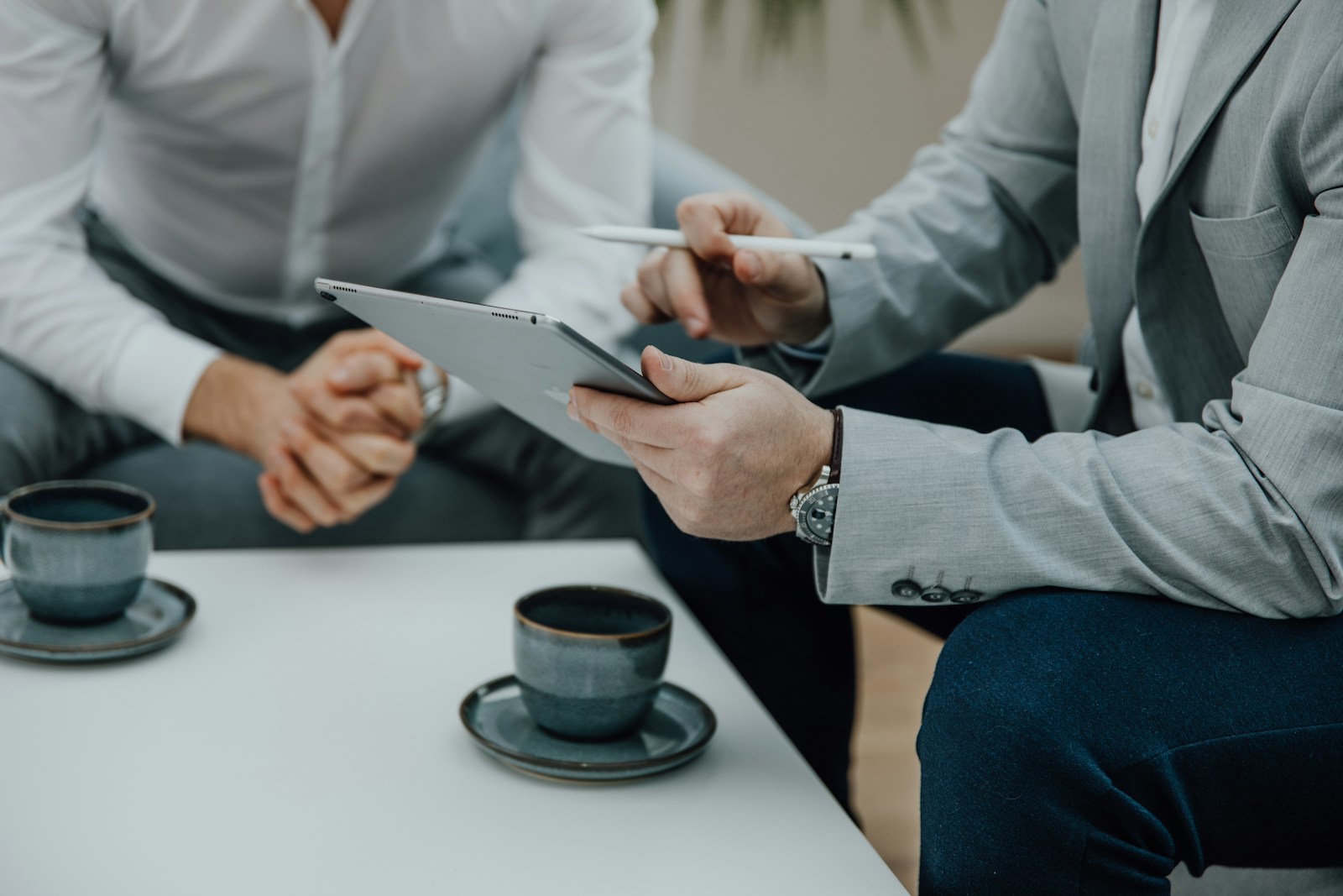two men sitting at a table with a tablet, business